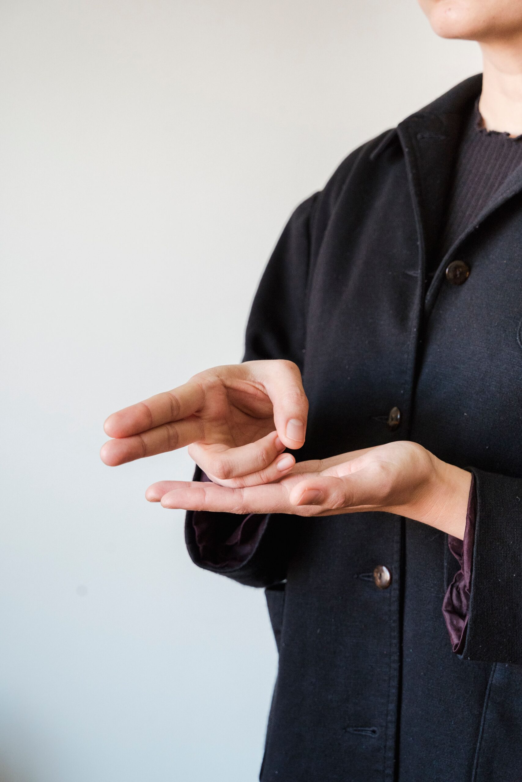 Close-up of hands demonstrating sign language gestures in a modern jacket.